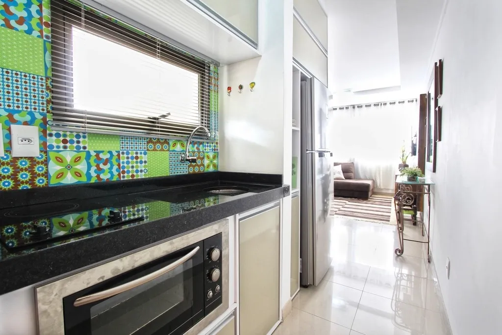 Cozinha limpa e com a bancada livre, fotografada na horizontal, com a sala ao fundo