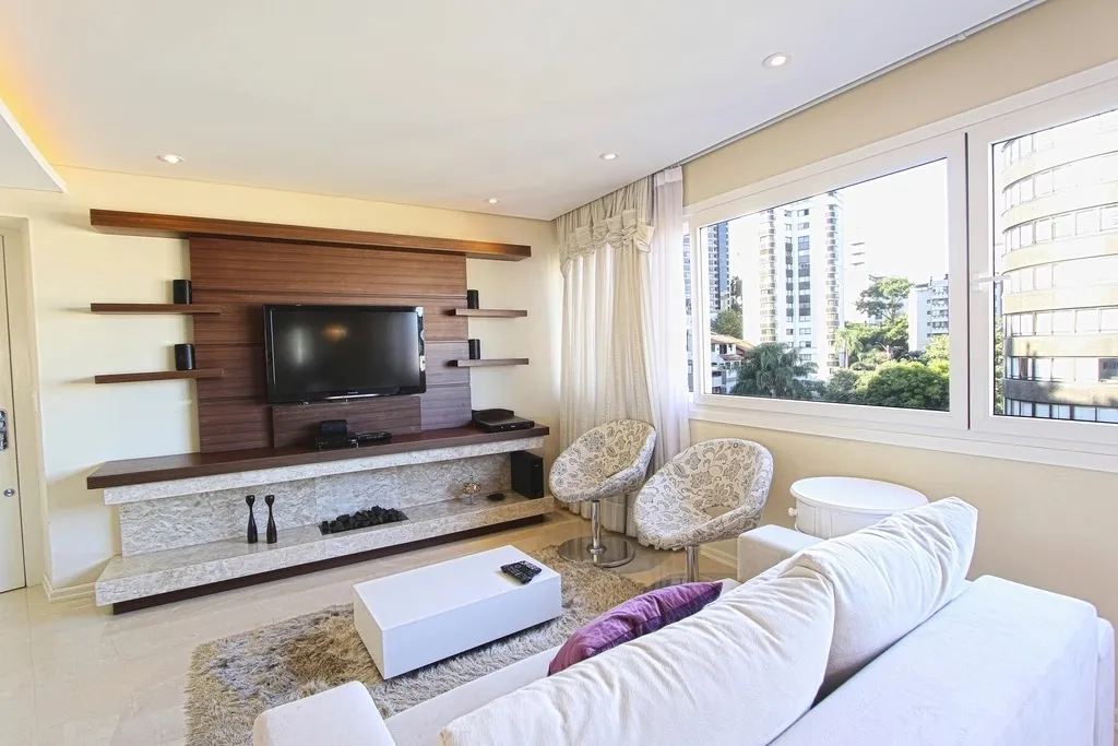 Sala de apartamento iluminada pela luz do dia, com janelas grandes e cortinas abertas